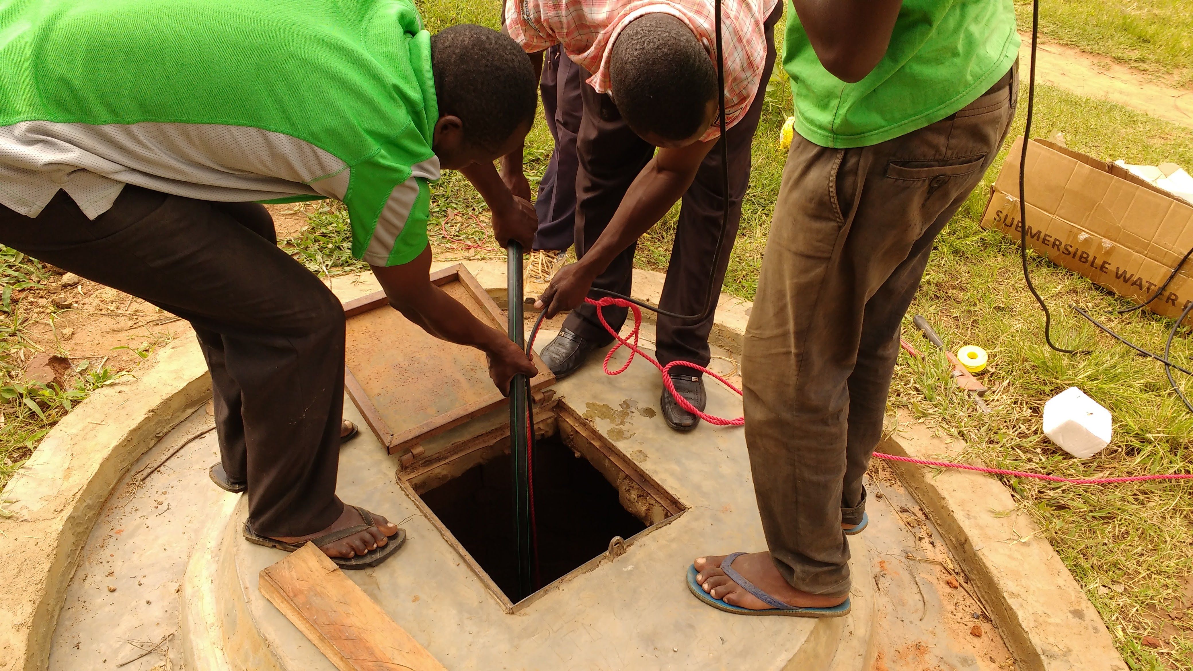 Lowering a pump into the water well at Amor Village, Tororo, Uganda